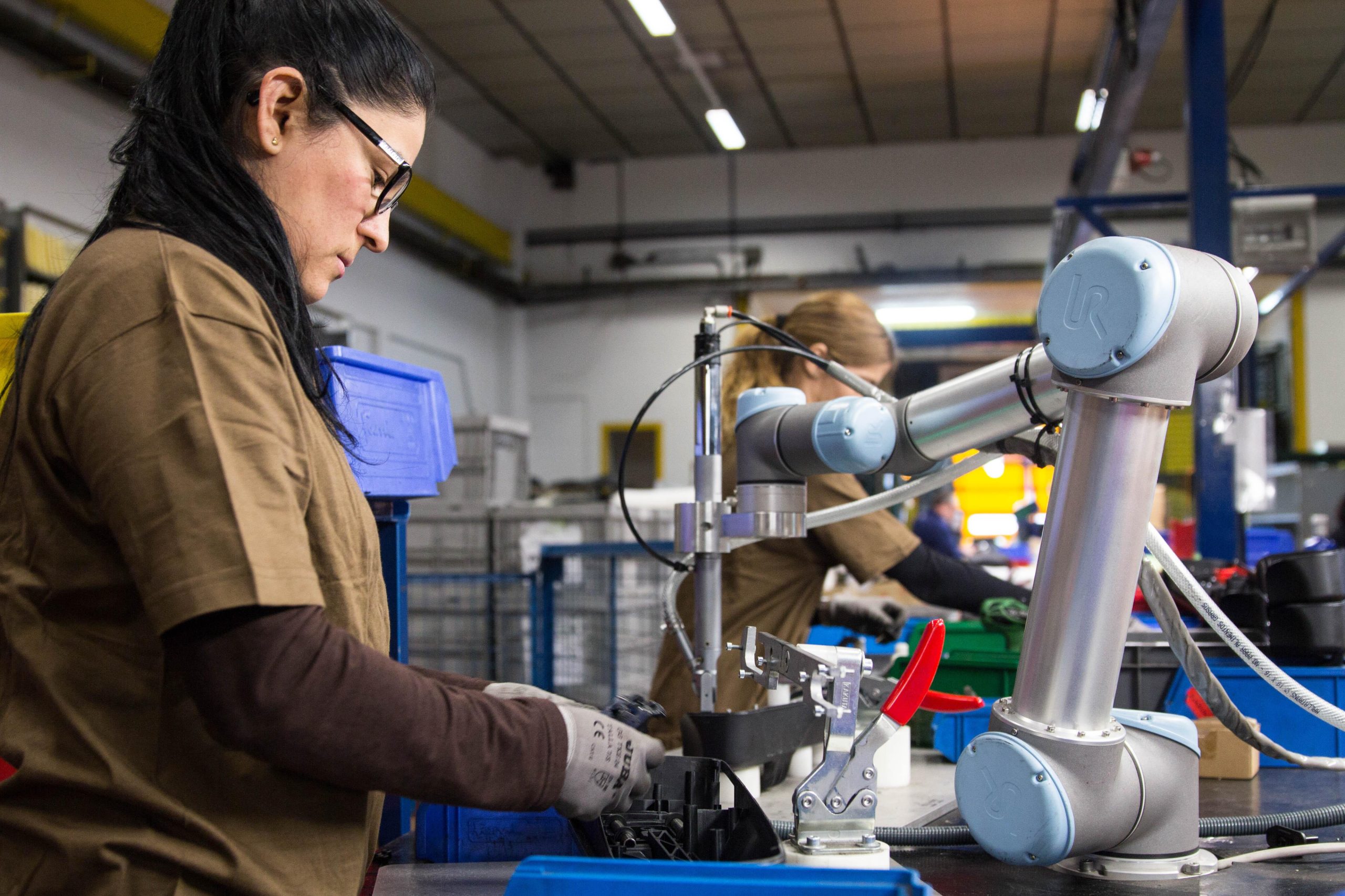 pekerja berdampingan dengan robotic arm.